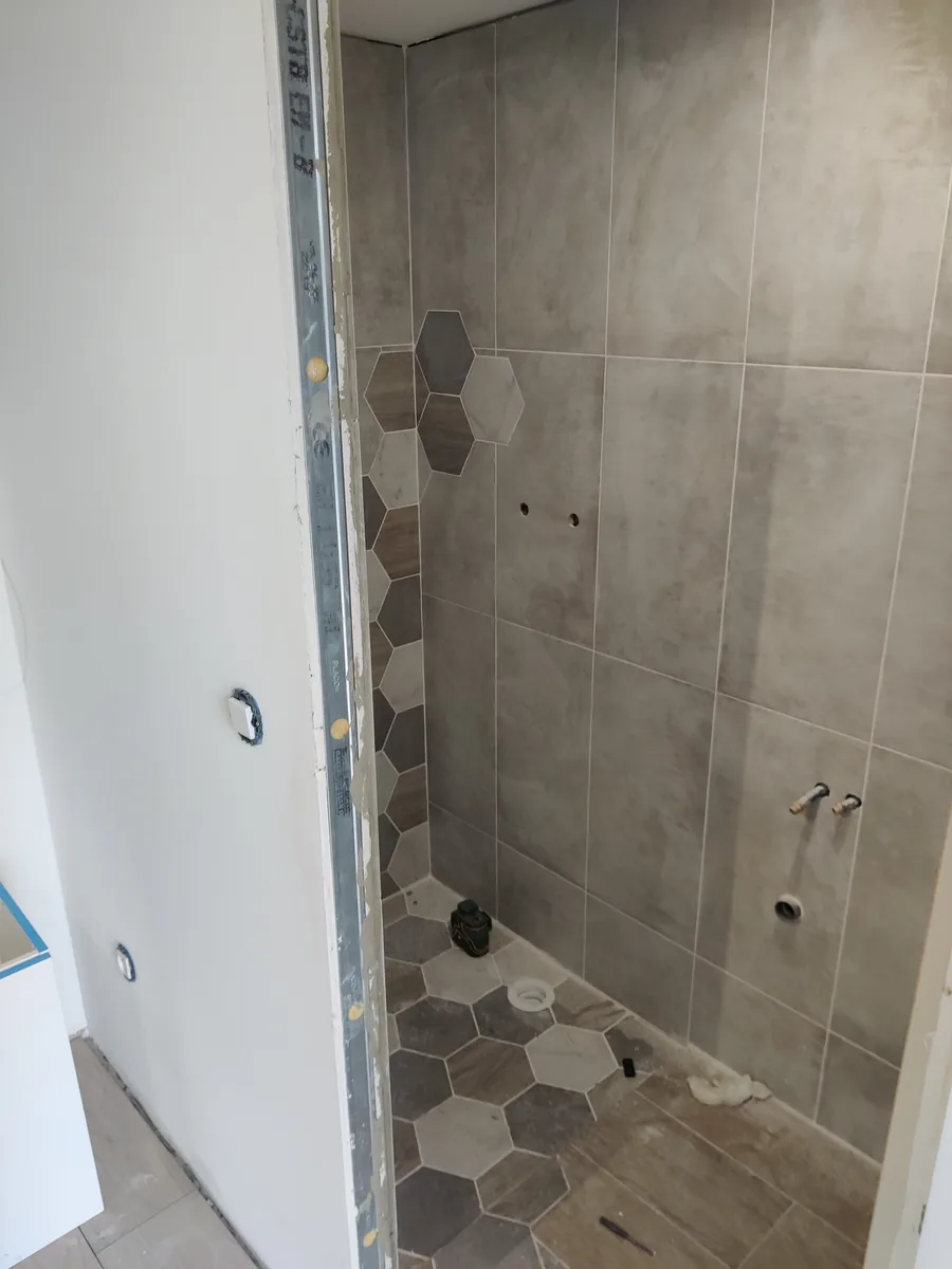Faïence de la douche en cours de pose, frise hexagonale en attente