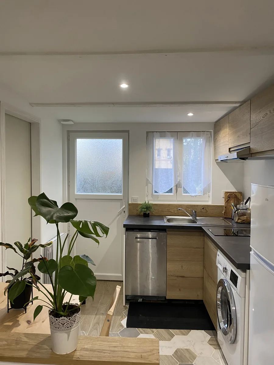 Cuisine équipée du studio avec lave-linge intégré et plan de travail sombre