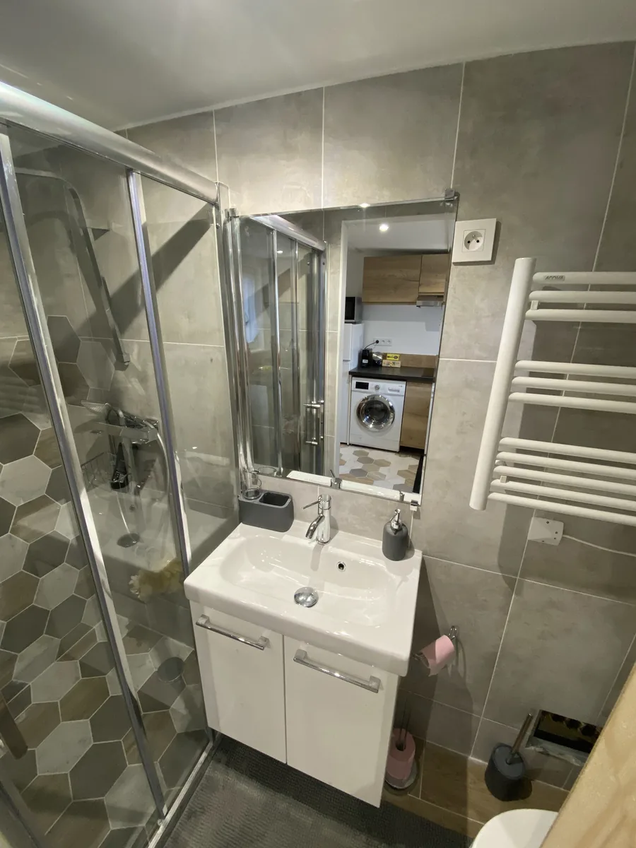 Salle d’eau du studio : douche, meuble vasque et sèche-serviettes
