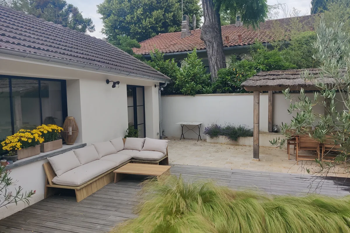 Coin repas extérieur sous la pergola, olivier planté en premier plan
