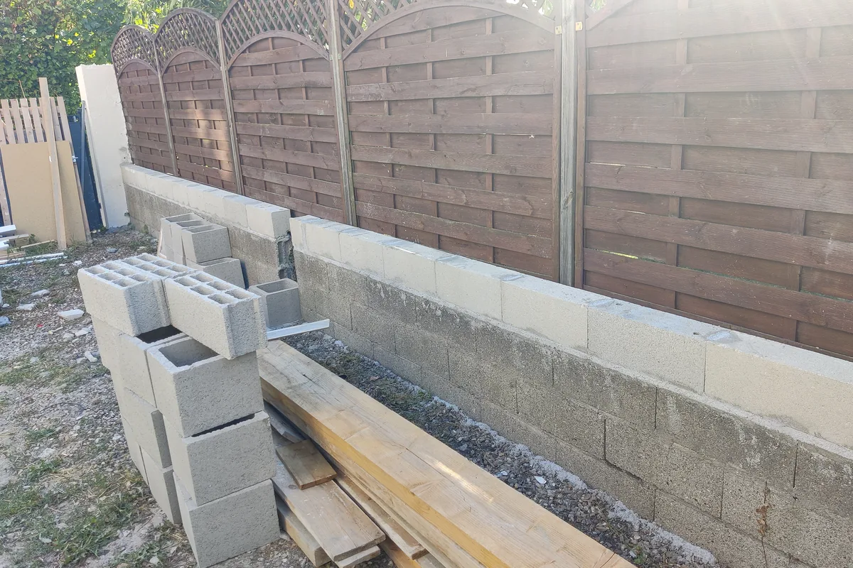 Montage du mur en blocs béton le long de la limite séparative