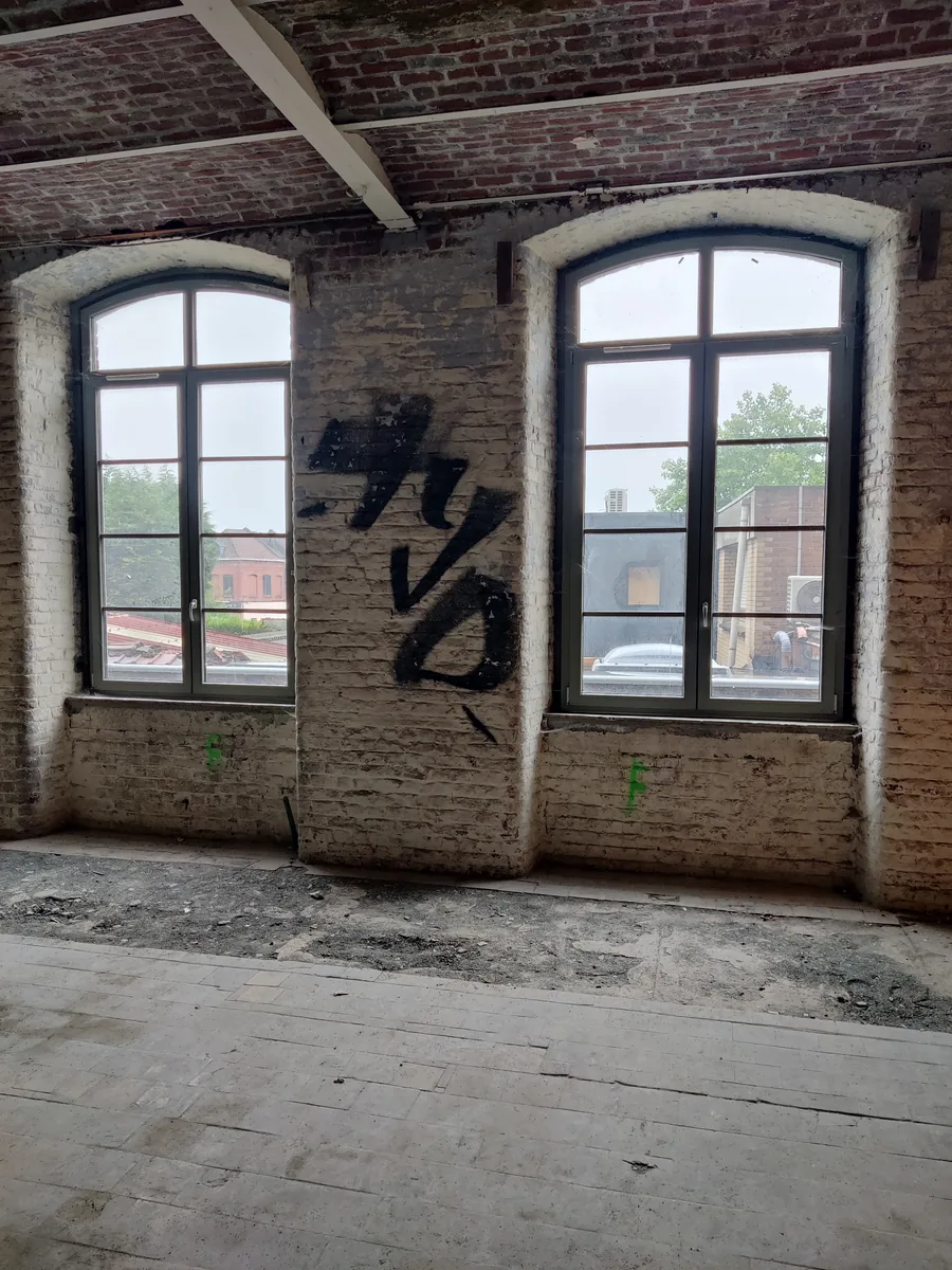 La friche avant travaux : maçonnerie de brique, baies cintrées et graffitis d’origine