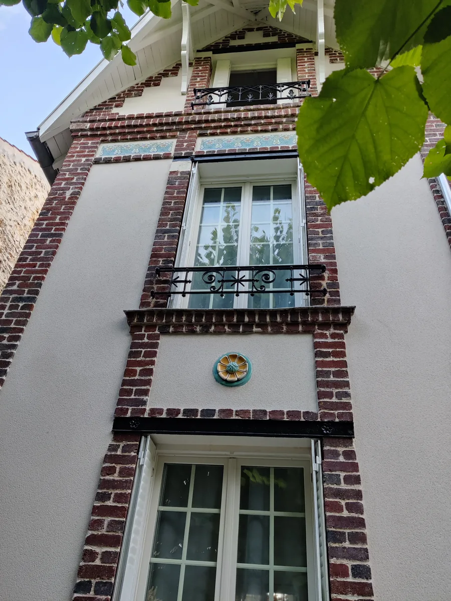 Façade restaurée : brique, enduit et frises en céramique d’origine conservées
