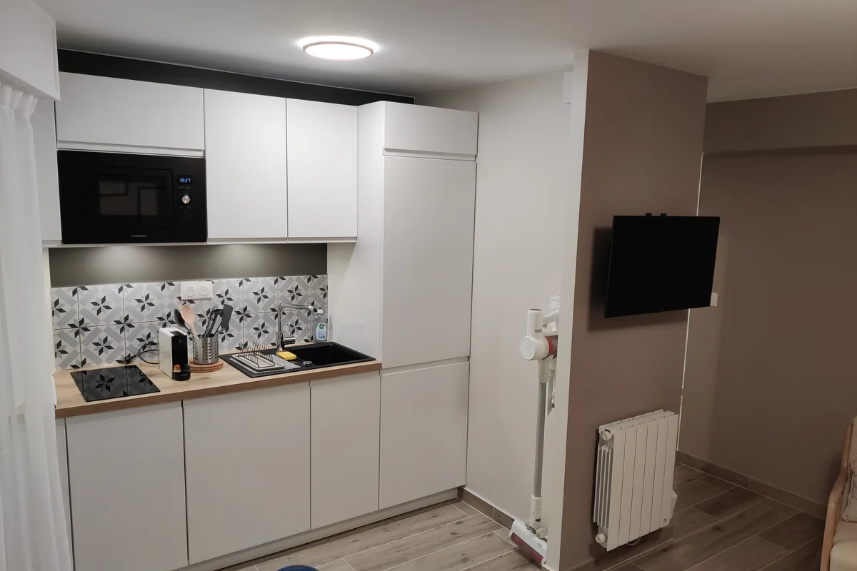 Cuisine blanche équipée, crédence à motifs et plan de travail bois