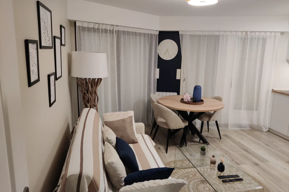 Pièce de vie rénovée avec cadres, rideaux et assise en tissu clair