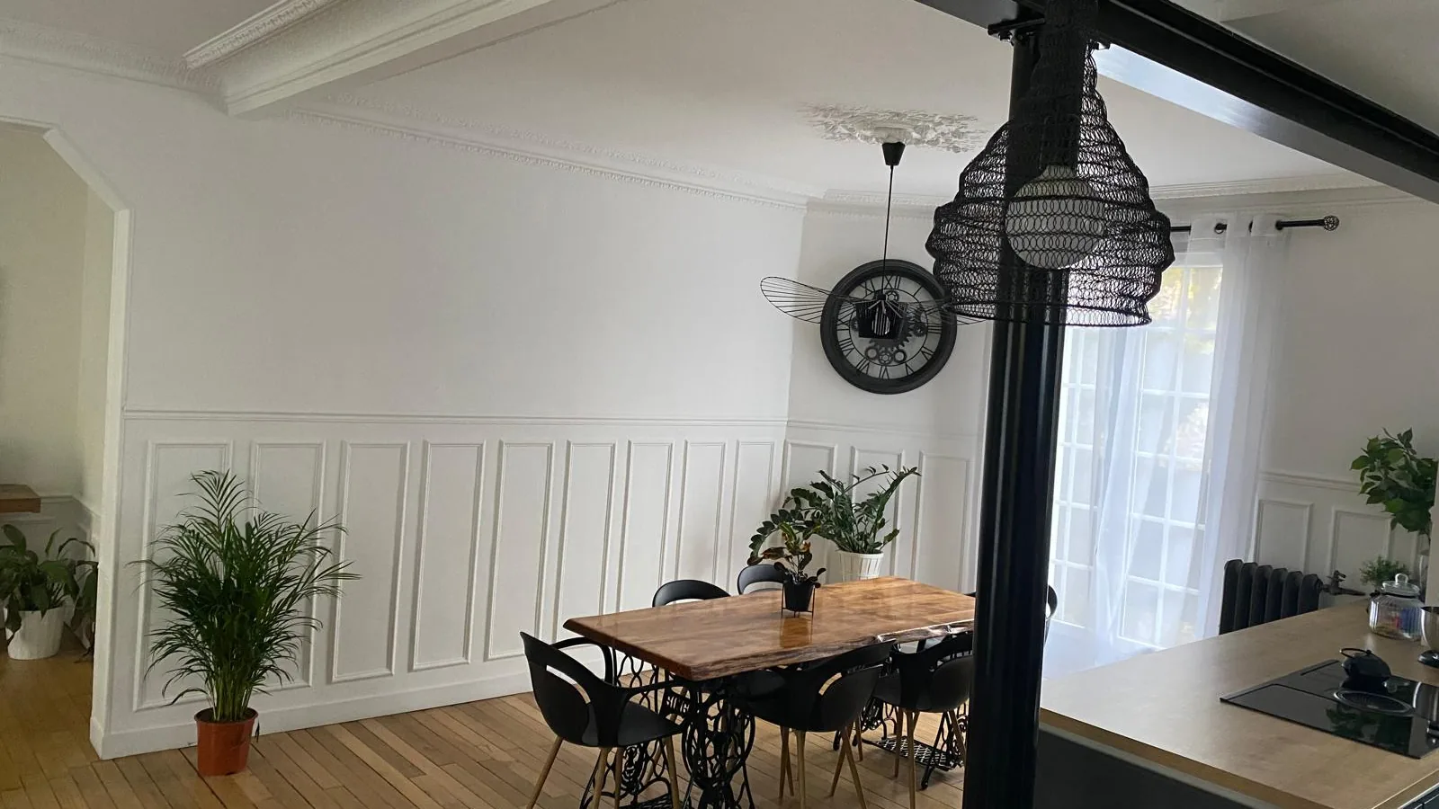 Séjour rénové avec poutre métallique noire apparente, soubassement mouluré et parquet chêne
