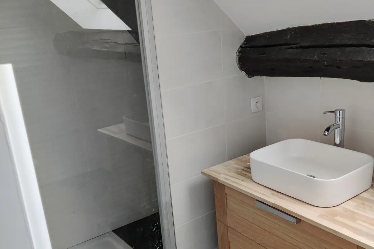 Salle de bain terminée sous rampant : douche à l’italienne, poutre peinte et meuble bois