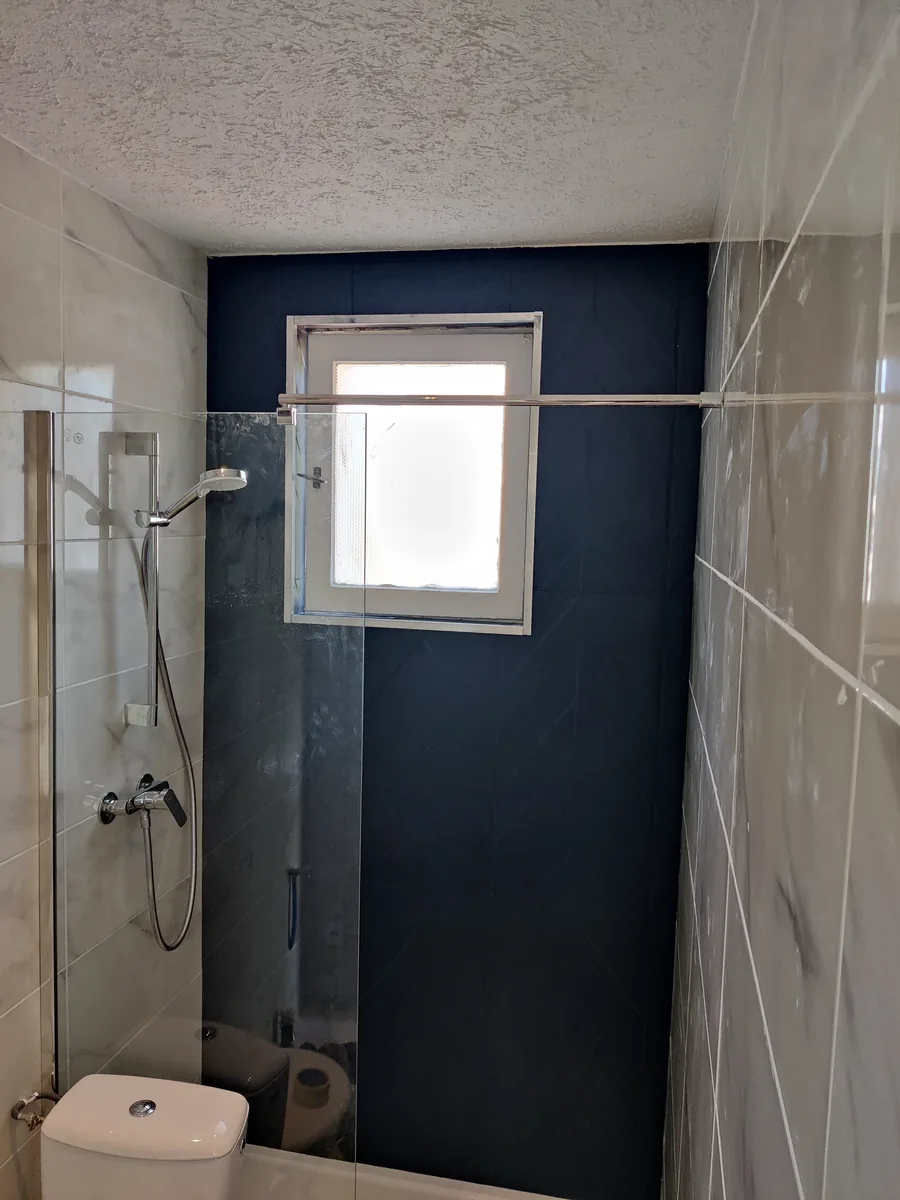 Salle d’eau terminée : niche carrelée bleu nuit et faïence effet marbre
