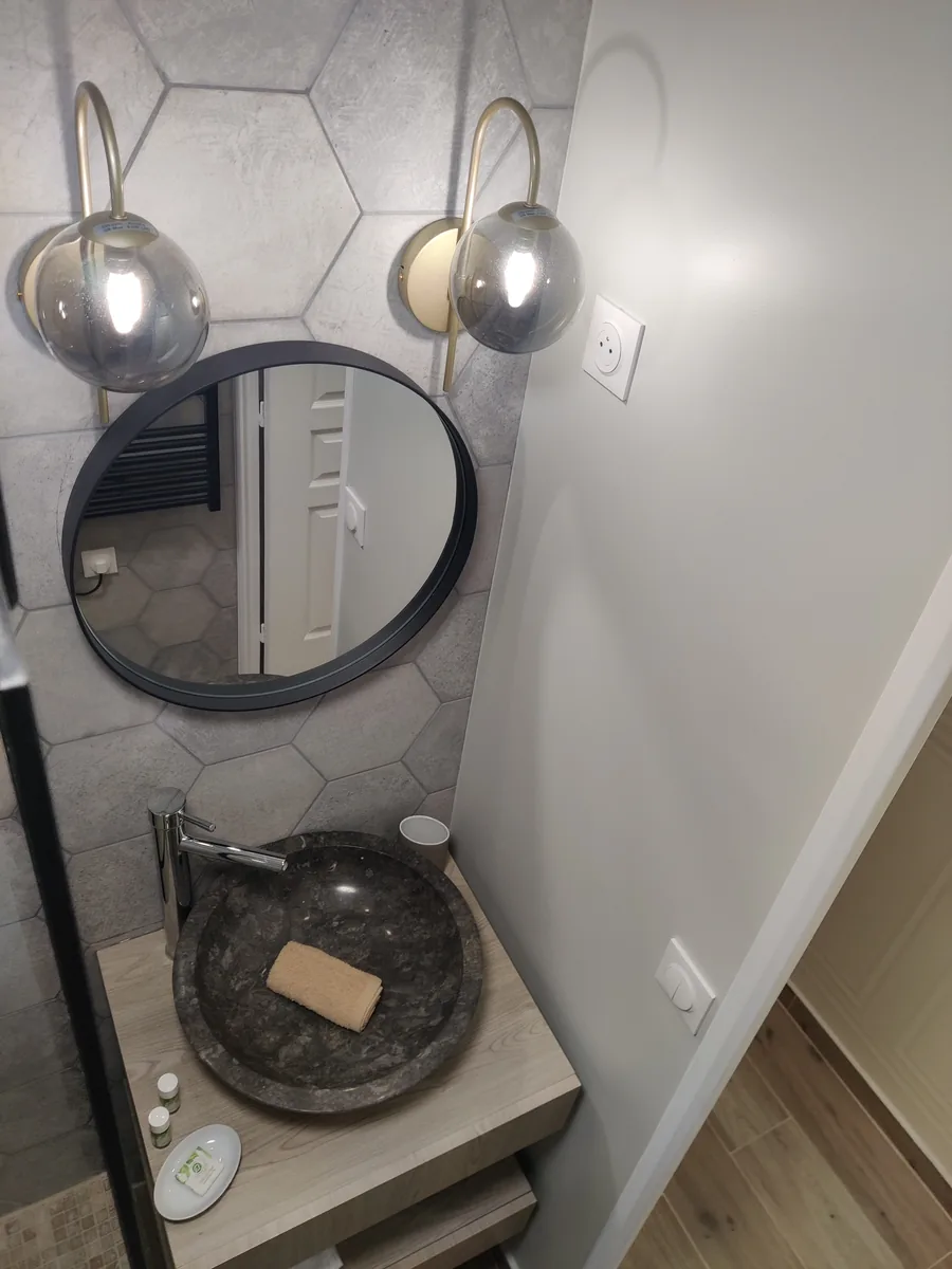 Détail de finition : vasque en pierre, miroir rond et appliques